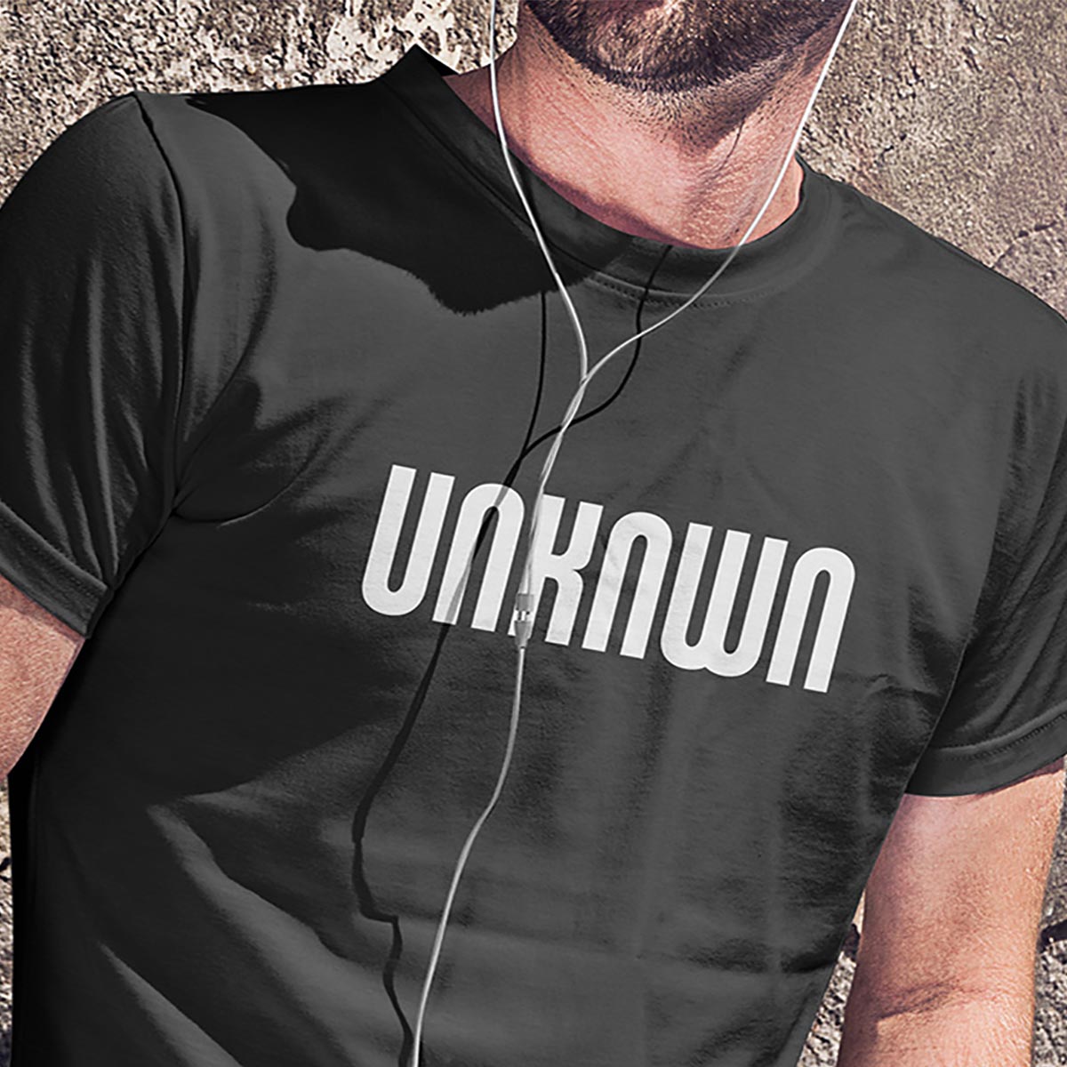 Man in a black tee shirt with the Unknwn logo in white.